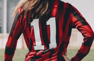 back of a female football player posing wearing a red and black vertical striped shirt printed with logo printed in white ink New DTF process launched by Resolute
